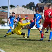 Sheringham Town player Jordan Forbes, far right, gets one past the Ely keeper.